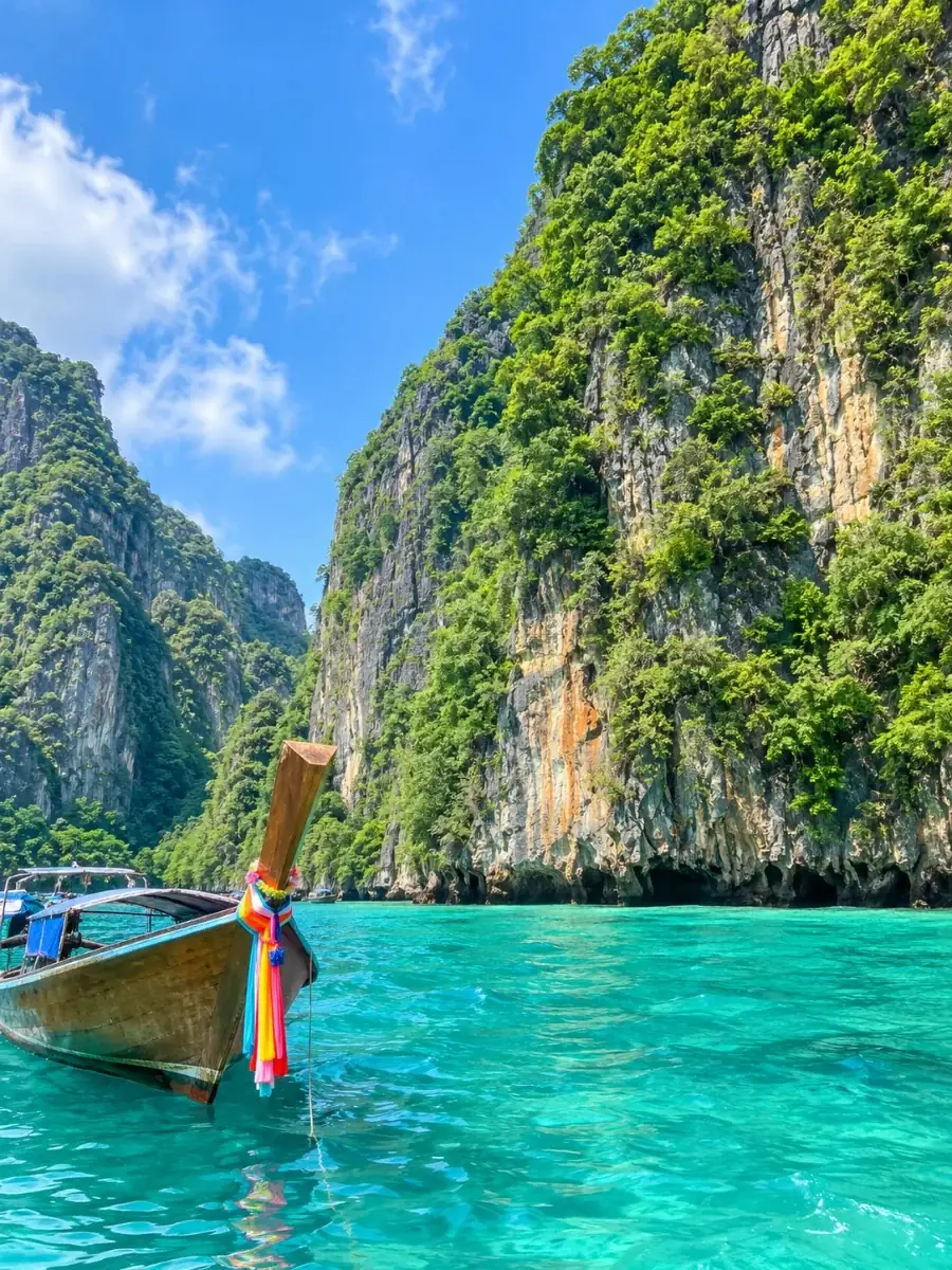 Acantilados de caliza de Ko Phi Phi Le cubiertos de jungla sobre aguas turquesas, con un barco longtail de cintas por delante